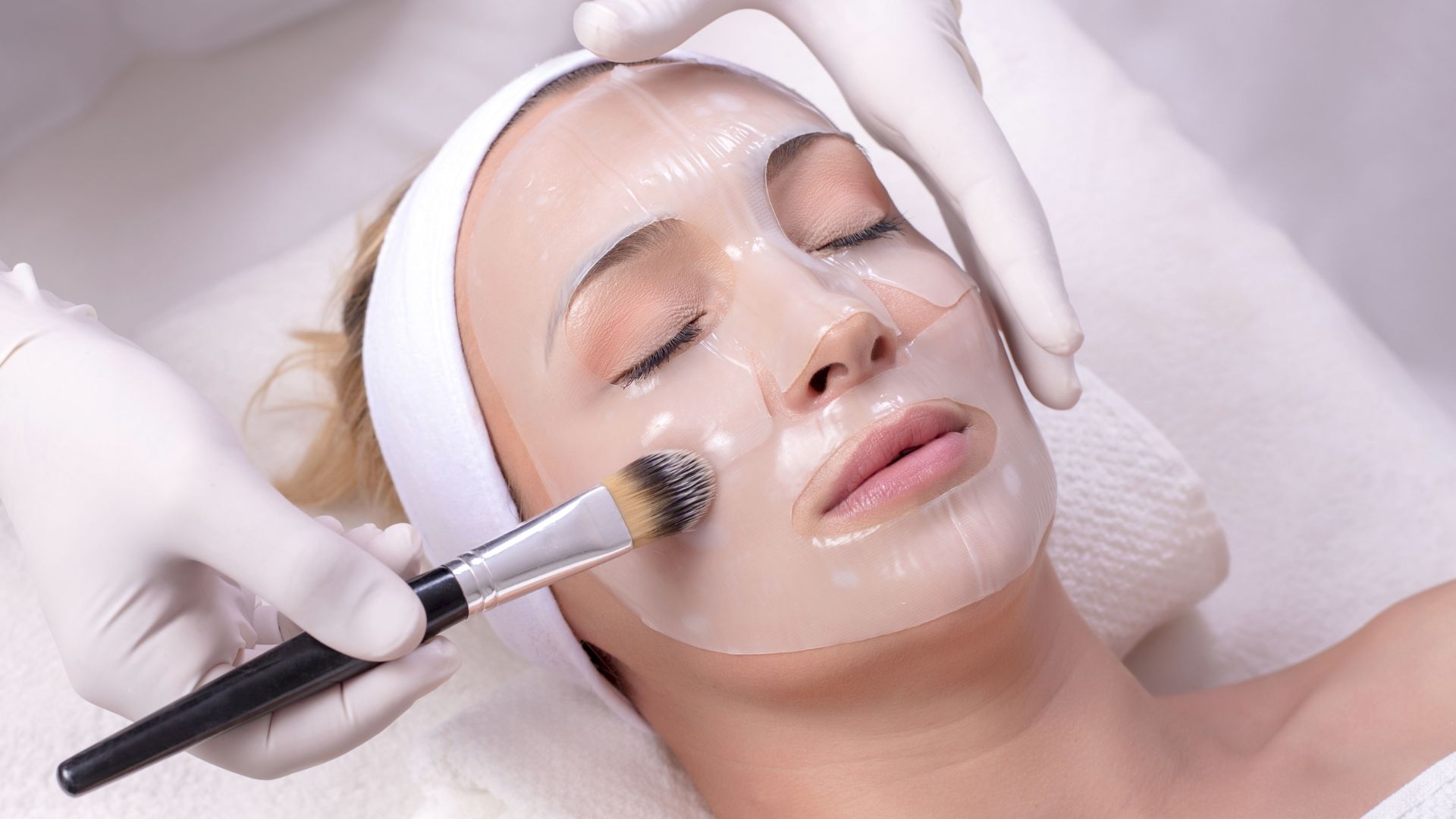 A woman getting a facial mask with a brush